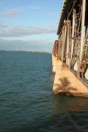 Laze in pristine blue-green water, feeling a whisper of breeze across your sun-warmed face, and gaze at the Old Bahia Honda Bridge rising stoically against a cloudless sky.